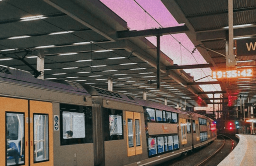 Image of a train in Sydney, taken at Parramatta Station. The sky is colored pale pink at sunset.