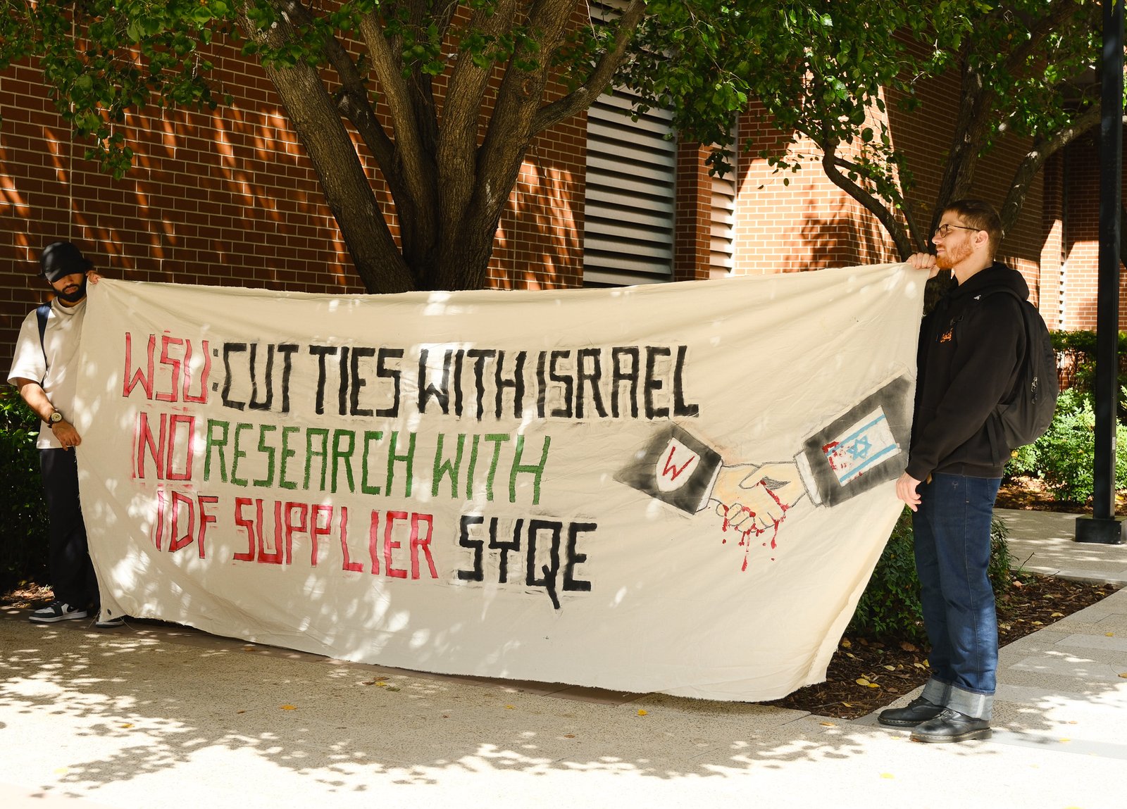 (Student protestors holding a banner and Palestinian flag, image by Eleanor Cooper, 2025)